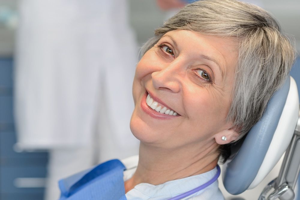 Grey-haired woman smiling in the dentist's chair